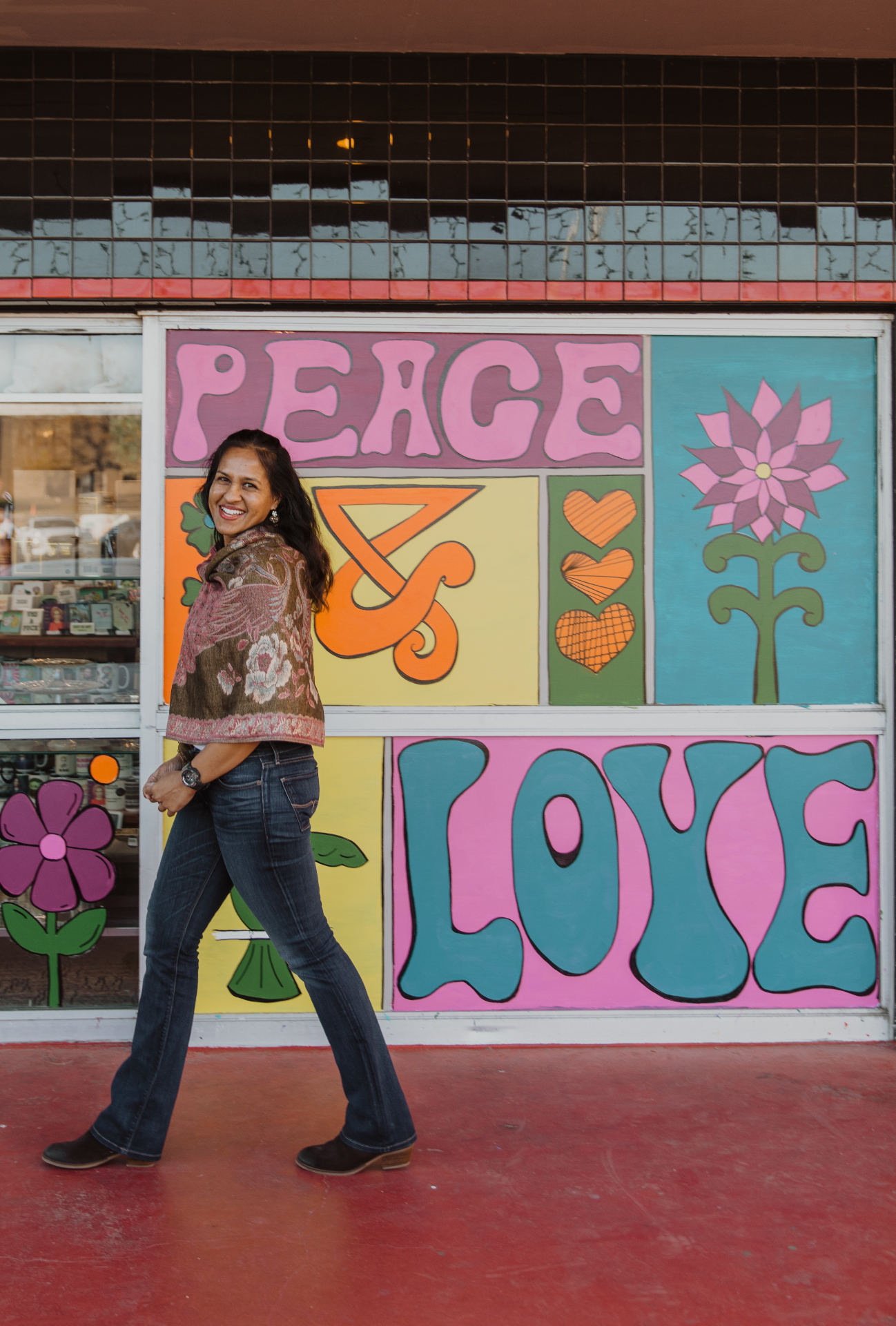Kara, founder of Dolce Flowers in Greenville, SC, walking past a colorful Peace and Love flower mural