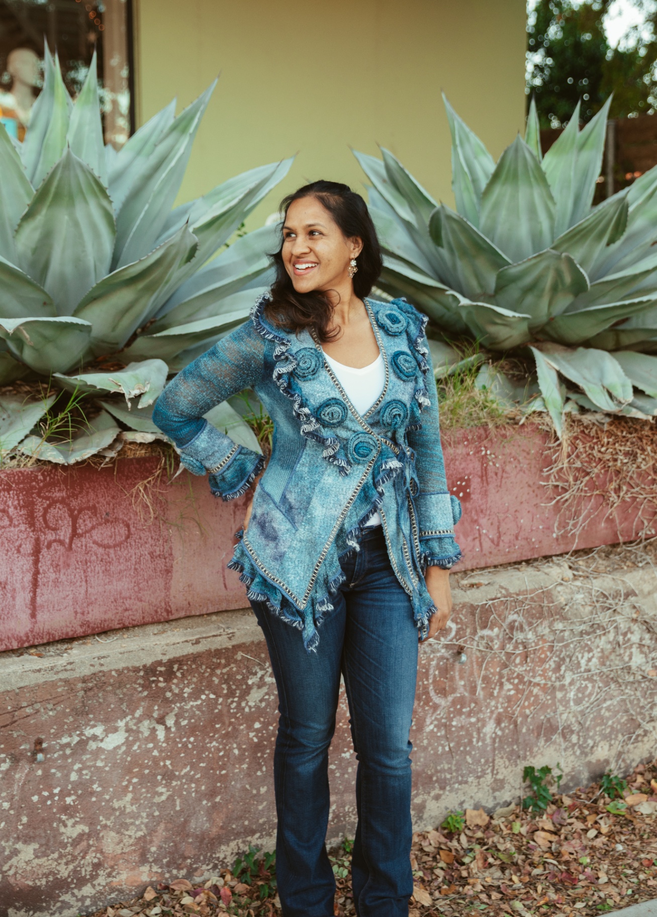Kara, founder of Dolce Flowers in Greenville, SC, smiling beside large agave plants
